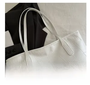 Detail view of white crocodile pattern tote bag featuring high-quality leather texture