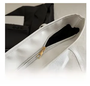 Detail view of smooth golden metal zipper and crocodile embossed texture on white tote bag
