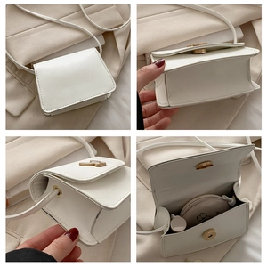 Detail view of mini white crossbody bag with golden butterfly buckle and inner storage