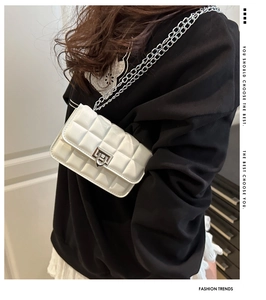 Detailed view of white quilted chain crossbody bag with silver twist lock on female model