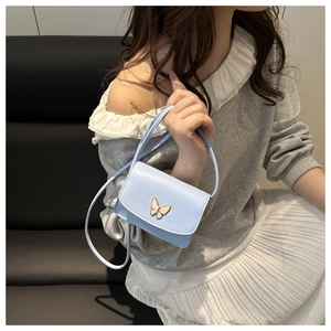 Detail of light blue mini square crossbody bag with decorative golden butterfly clasp