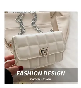 Detail of creamy white crossbody bag with quilted stitching and silver metal chain strap