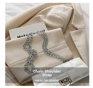 Close-up of white quilted patent leather mini bag with silver chain and metal push lock