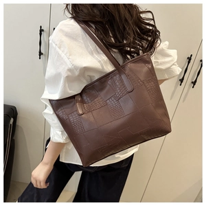 Close-up of brown tote bag featuring textured animal pattern patchwork and slim straps