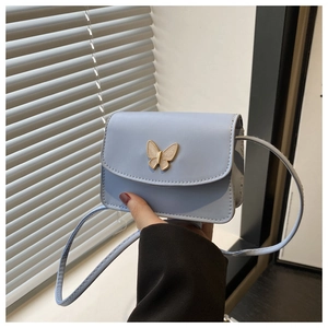Close-up of light blue mini bag with decorative butterfly clasp and pearl inlay details