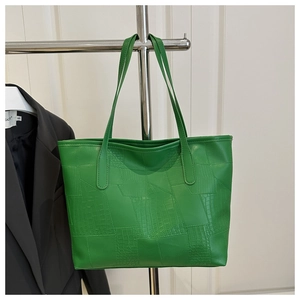 Detail of green crocodile texture faux leather tote bag hanging on silver stand