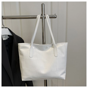 Detail view of the white tote bag featuring crocodile texture and patchwork craftsmanship