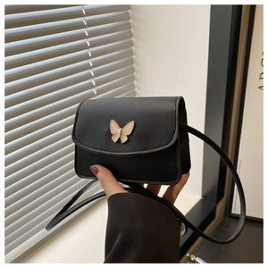 Detail of a mini black crossbody bag with a decorative gold butterfly metal clasp