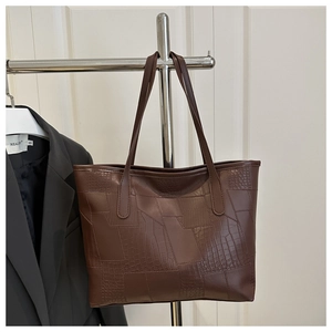 Detail of dark brown tote bag featuring patchwork faux crocodile texture and smooth finish