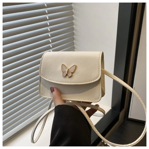 Close-up of butterfly metal buckle with pearl finish on a beige crossbody flap bag