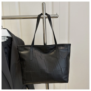 Detail of black tote bag featuring mixed crocodile and snake skin textured faux leather