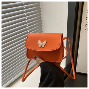 Detail of orange crossbody bag featuring a white enamel butterfly hardware and PU leather