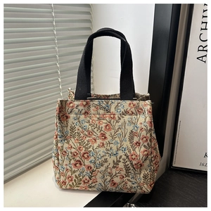 Close-up of vintage floral jacquard tote bag with black handles and zipper details