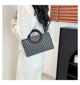 Detailed view of monogram print crossbody bag with circular handle on model side