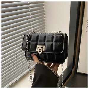 Detail of black quilted leather mini square bag with silver metal chain strap and twist lock