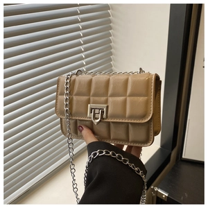 Detail of beige quilted mini crossbody bag with glossy texture and silver chain strap