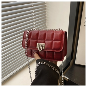 Detail of red quilted leather mini bag featuring shiny finish and silver metal lock
