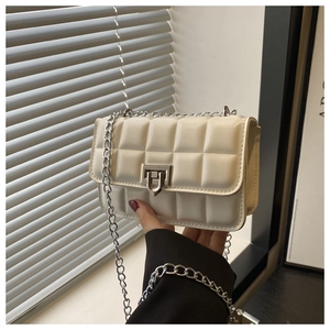 Detail of off-white quilted crossbody bag with silver twist lock and metal chain strap