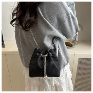 Detail of black drawstring bucket bag with textured fabric and pearl chain strap