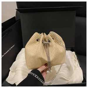 Detail of beige corduroy bucket bag with drawstring, silver chain, and pearl accents