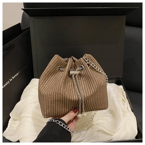 Detail of corduroy bucket bag featuring woven texture, silver chain and pearl drawstring