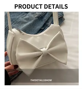 Detail shot of a white PU leather shoulder bag with a large decorative ribbon bow