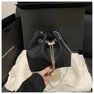Detailed view of black corduroy bucket bag featuring silver chains and pearl drawstring tassels