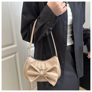 Close-up of beige shoulder bag with large bow detail and sleek leather texture