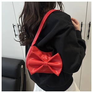 Gros plan sur le sac à main rouge vif avec nœud en cuir mat et bandoulière élégante