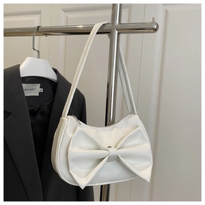 Detail of white bow hobo bag featuring a large ribbon accent and crescent shoulder strap