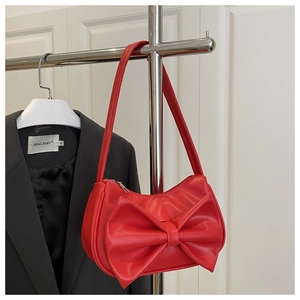 Close-up of a stylish red crossbody bag featuring a large decorative bow on a metal rack