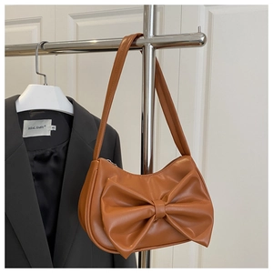 Close-up of brown faux leather shoulder bag featuring a large decorative 3D bow detail