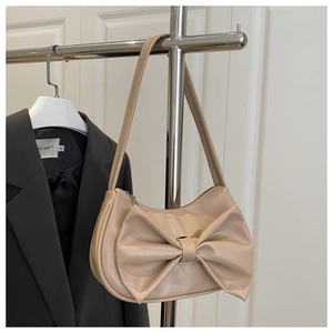 Detail view of the cream PU leather half-moon bag featuring a large decorative bow design