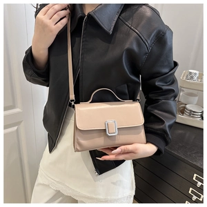 Détail d'un sac bandoulière beige minimaliste avec boucle argentée porté par un mannequin