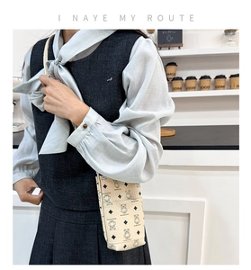 Detail of beige mini bucket phone bag with cartoon bear print and leather texture
