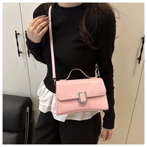 Détail d'un sac bandoulière rose avec boucle argentée porté par un mannequin dans un salon