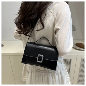 Detailed back view of a woman wearing a black flap crossbody bag with silver buckle
