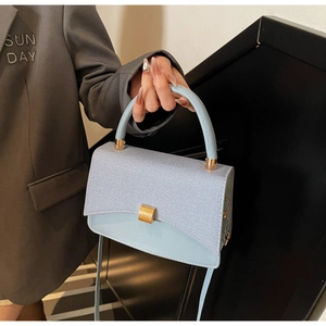 Detail of light blue PU leather bag with gold buckle and stylish mixed textures
