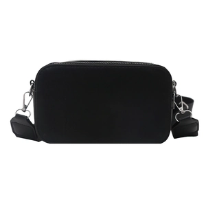 Minimalist black rectangular camera bag with wide crossbody strap and silver hardware