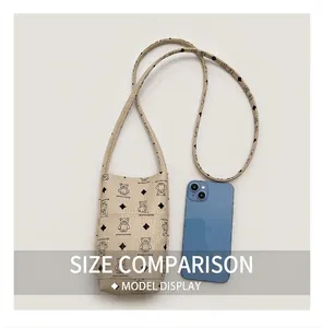 Detail of cream mini phone bag showing litchi texture and cute bear pattern print