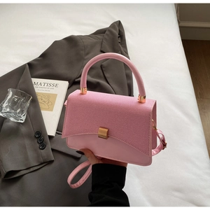 Detailed view of pink crossbody bag with textured flap and elegant gold hardware details