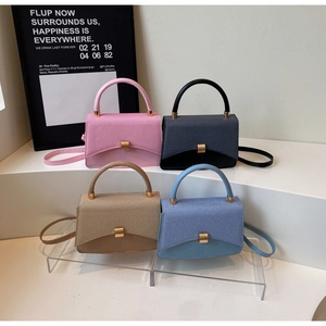 Detail of minimalist square handbags in multiple colors with golden buckles on a white display