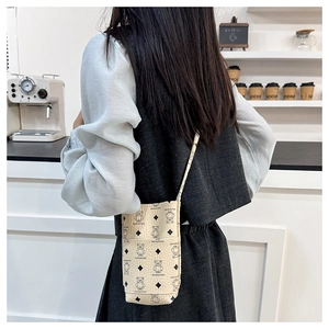 Detail of beige crossbody phone bag featuring bear print and textured synthetic leather