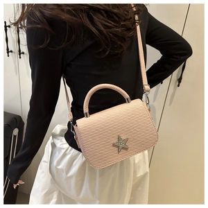 Pink mini crossbody bag featuring a silver sequined star and textured finish on a model