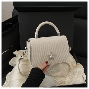 Close-up of white woven leather handbag featuring a sparkling rhinestone star detail