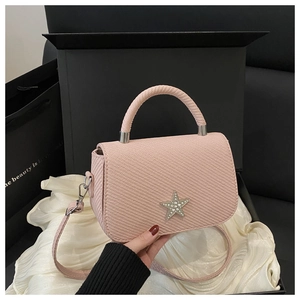 Detailed view of a mini pink crossbody bag with a rhinestone star and handle on silk fabric