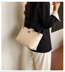 Detail shot of white quilted tote bag with silver chain strap and metallic clasp