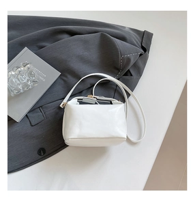 Détail du sac bandoulière en cuir blanc avec boucles dorées et fine lanière