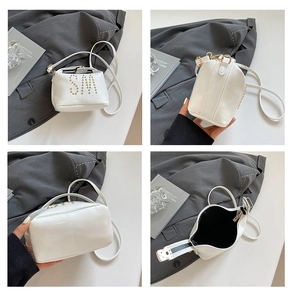 Détails d'un sac à bandoulière blanc avec rivets dorés et doublure intérieure noire