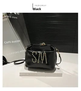 Détail d'un sac cabas noir brillant avec logo SM clouté doré et fermoir métallique